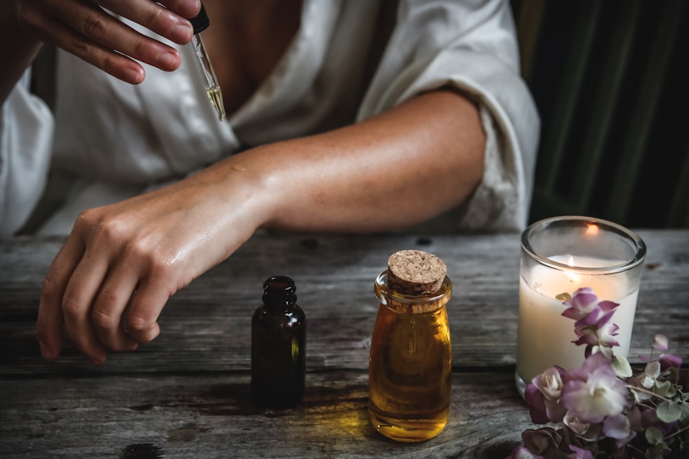 Amber oil bottles and a lit candle on weathered wood