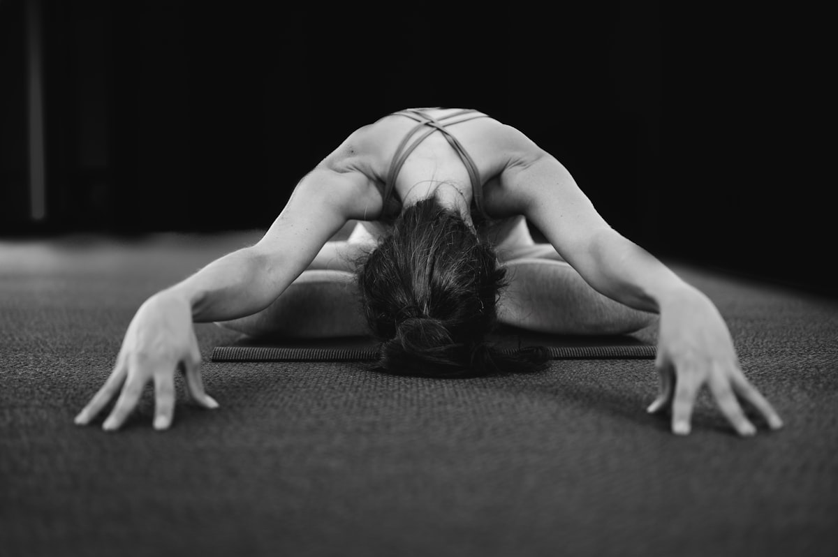 A black and white photograph of a practitioner folded forward in child's pose
